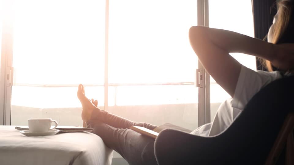 A lady sitting back and relaxing with a book and a coffee